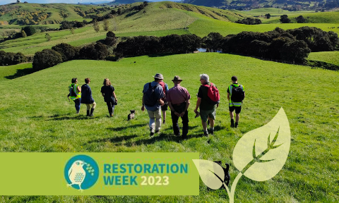 A group of people and dogs walk down a grassy hill, overlaid with the title Restoration Week 2023